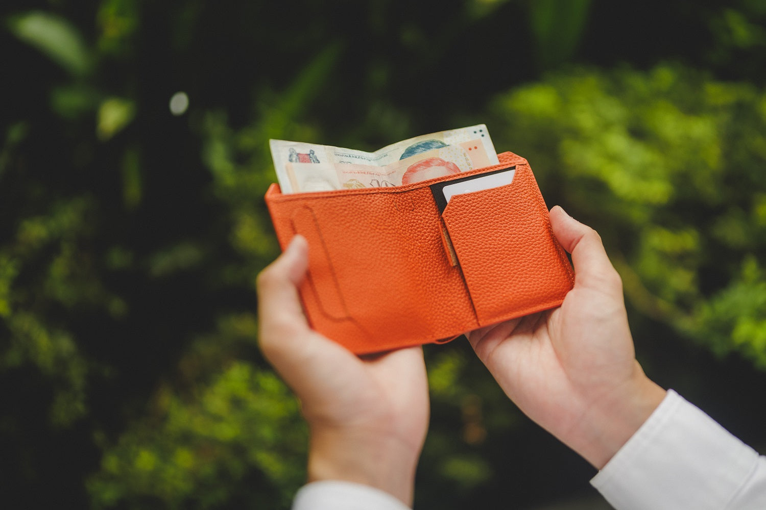 Orange kaizen wallet with money held by hands